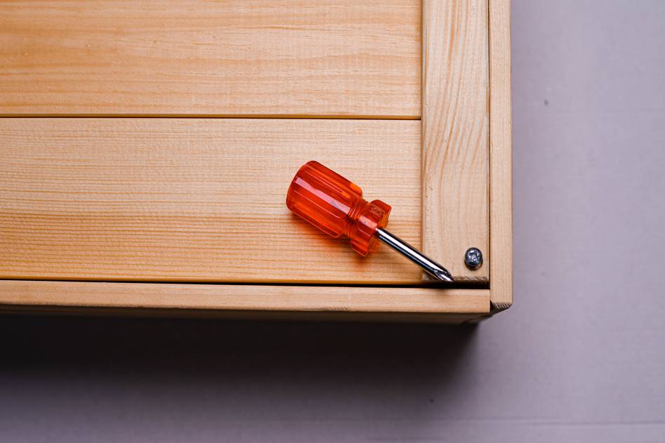 DIY homeowner tightening a pipe under a kitchen sink with common hand tools nearby